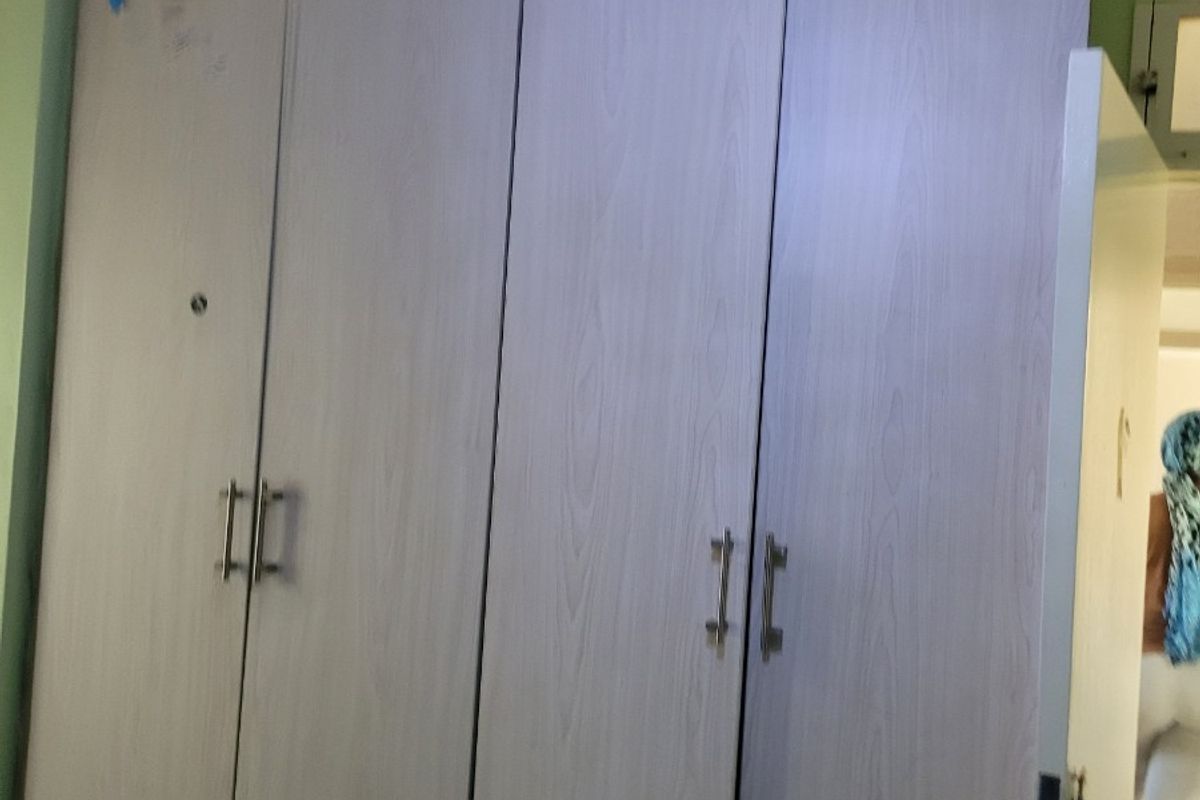 A bedroom featuring a light-toned wood grain built-in wardrobe with modern metal handles.