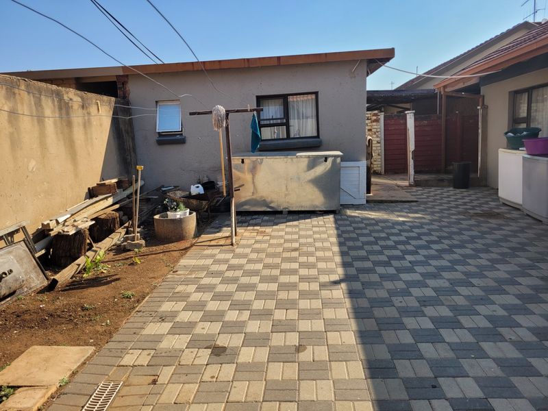A rear courtyard area featuring paved flooring, a boundary wall, and access to the main dwelling structure.