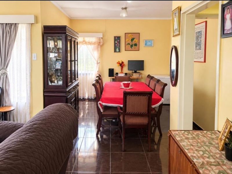 A dining room featuring dark tiled flooring and yellow walls, providing a functional space for family meals.