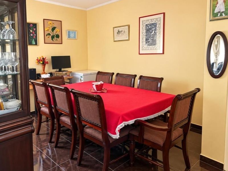 A dining room featuring dark tiled flooring and yellow walls, providing a functional space for family meals.