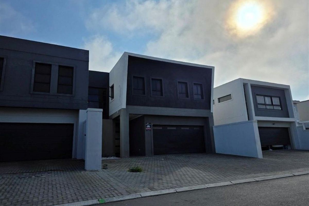 Modern multi-unit residential facade featuring contemporary dark and light exterior finishes, paved driveway access, and integrated double garages.