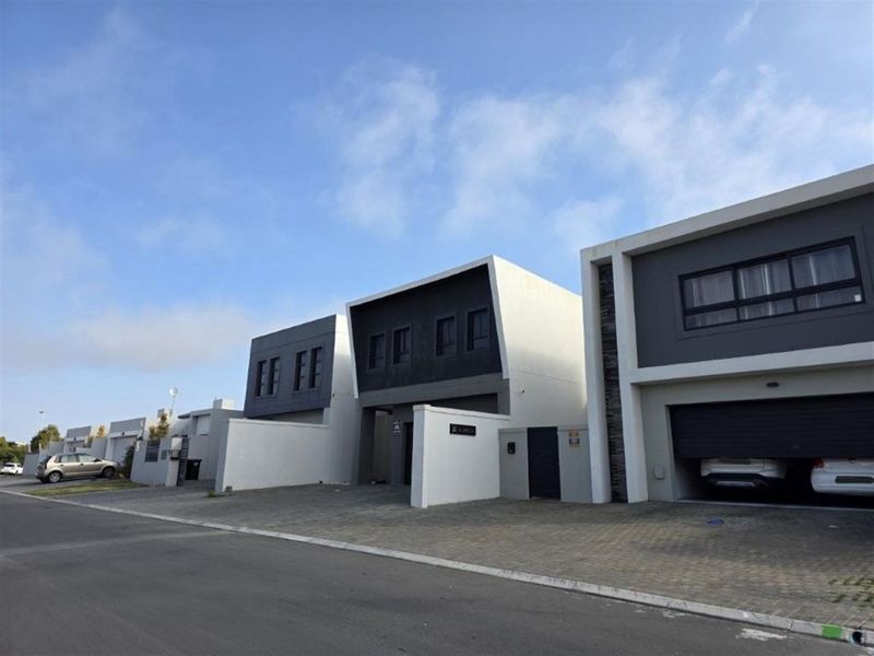 Modern double-storey residential townhouse facade featuring a paved driveway, secure automated garage, and contemporary architectural finishes.