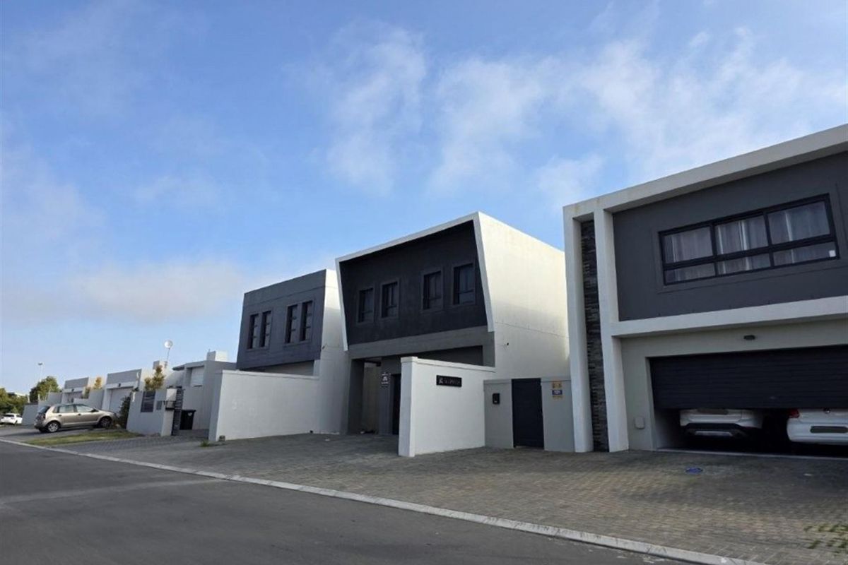 Modern double-storey residential townhouse facade featuring a paved driveway, secure automated garage, and contemporary architectural finishes.