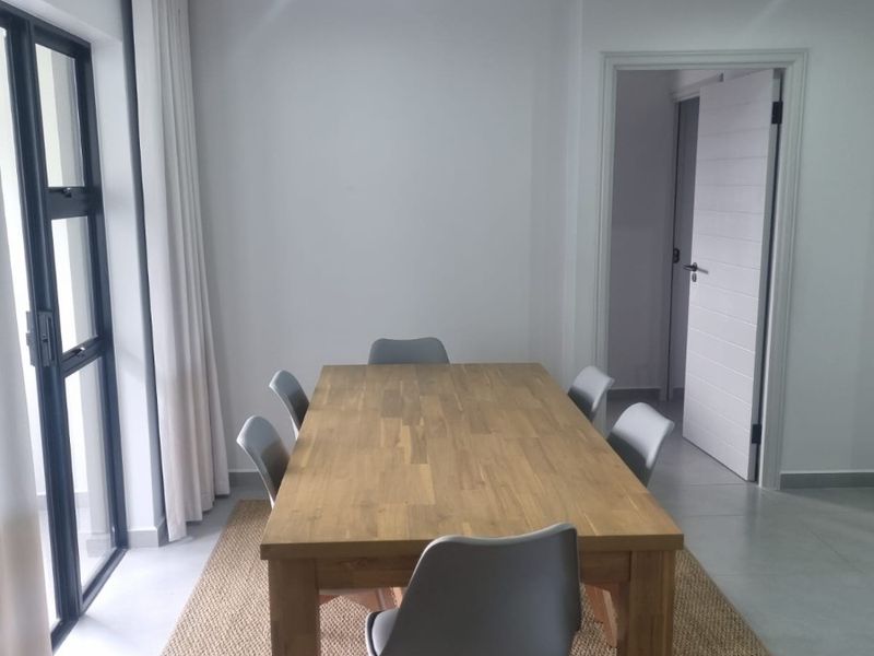 A bright dining area featuring tiled flooring, recessed lighting, and a large sliding glass door providing access to the exterior.