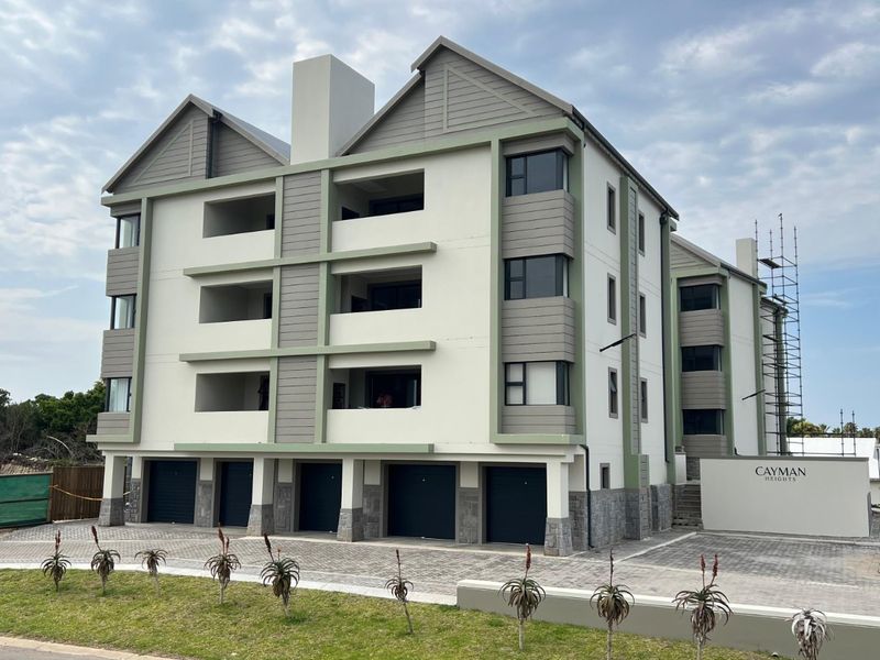 Modern multi-story apartment complex featuring a paved driveway, multiple ground-level garages, and private balconies with contemporary architectural finishes.