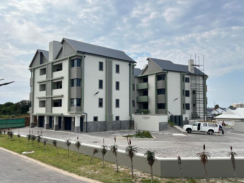 Exterior view of a modern multi-story apartment complex featuring paved driveway, stone base detailing, and metal roofing.