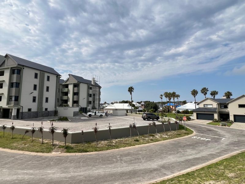 Exterior view of a modern apartment complex featuring a paved driveway, landscaped grounds, and surrounding residential neighborhood.