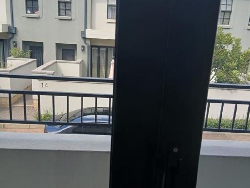 A view from a balcony overlooking a residential street and neighboring townhouses.