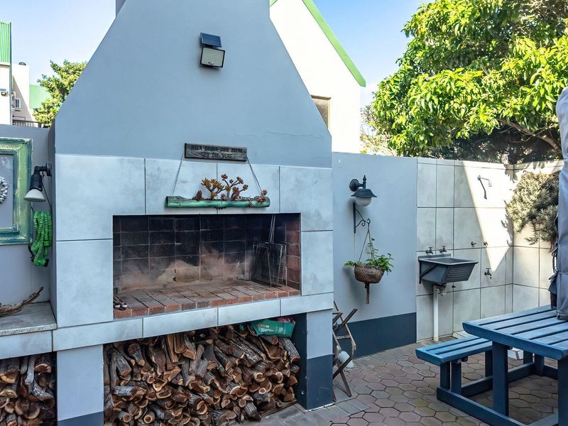 Outdoor entertainment area featuring a built-in brick braai, integrated sink, and paved flooring, ideal for alfresco dining and social gatherings.