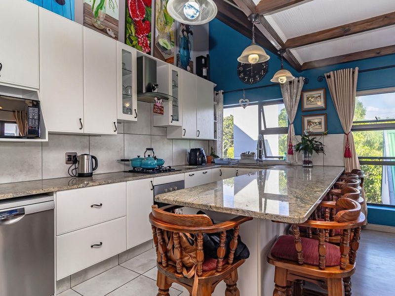 A well-appointed kitchen featuring granite countertops, built-in appliances, and exposed timber ceiling beams, offering a functional and characterful cooking and dining space.