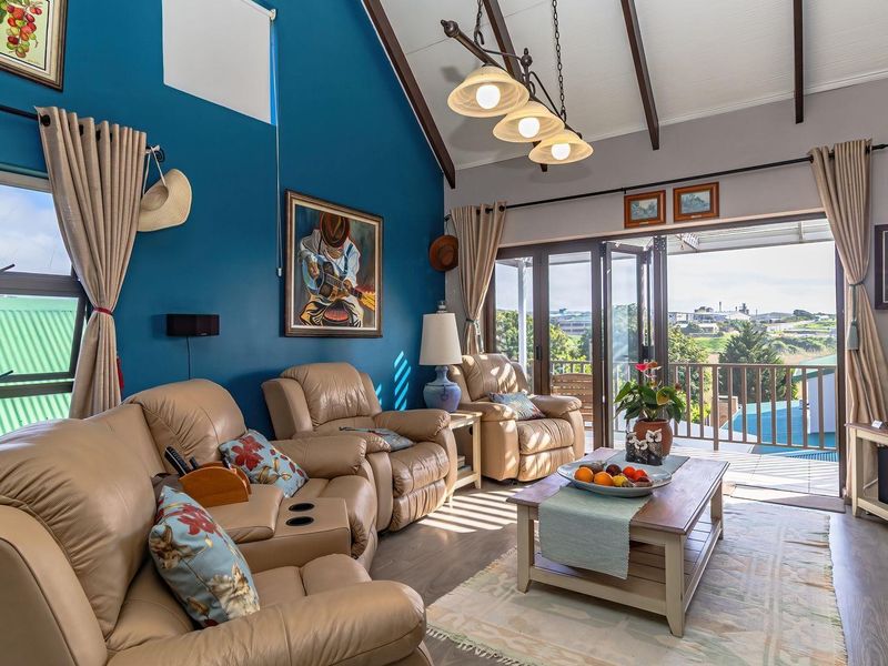 Spacious living room featuring a vaulted ceiling with exposed timber beams, laminate flooring, and bi-fold doors opening to an outdoor balcony area.