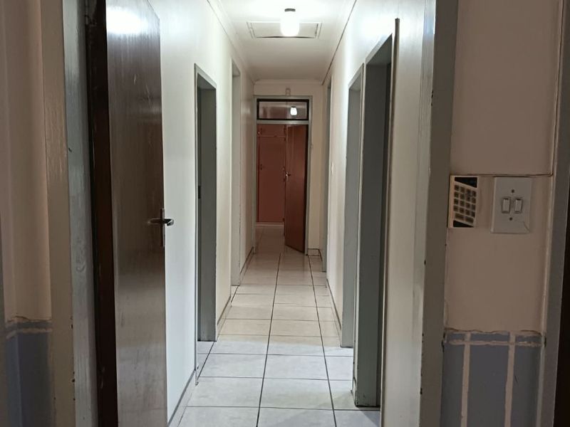 A functional interior hallway featuring tiled flooring, multiple internal access points, and a central ceiling light fixture.