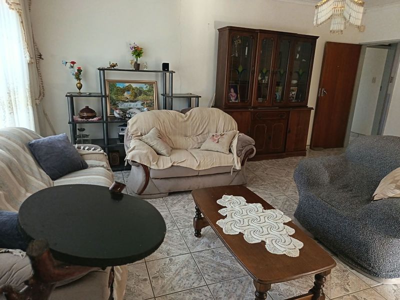 A living room featuring tiled flooring and a ceiling light fixture, showing signs of wear including a visible wall crack.