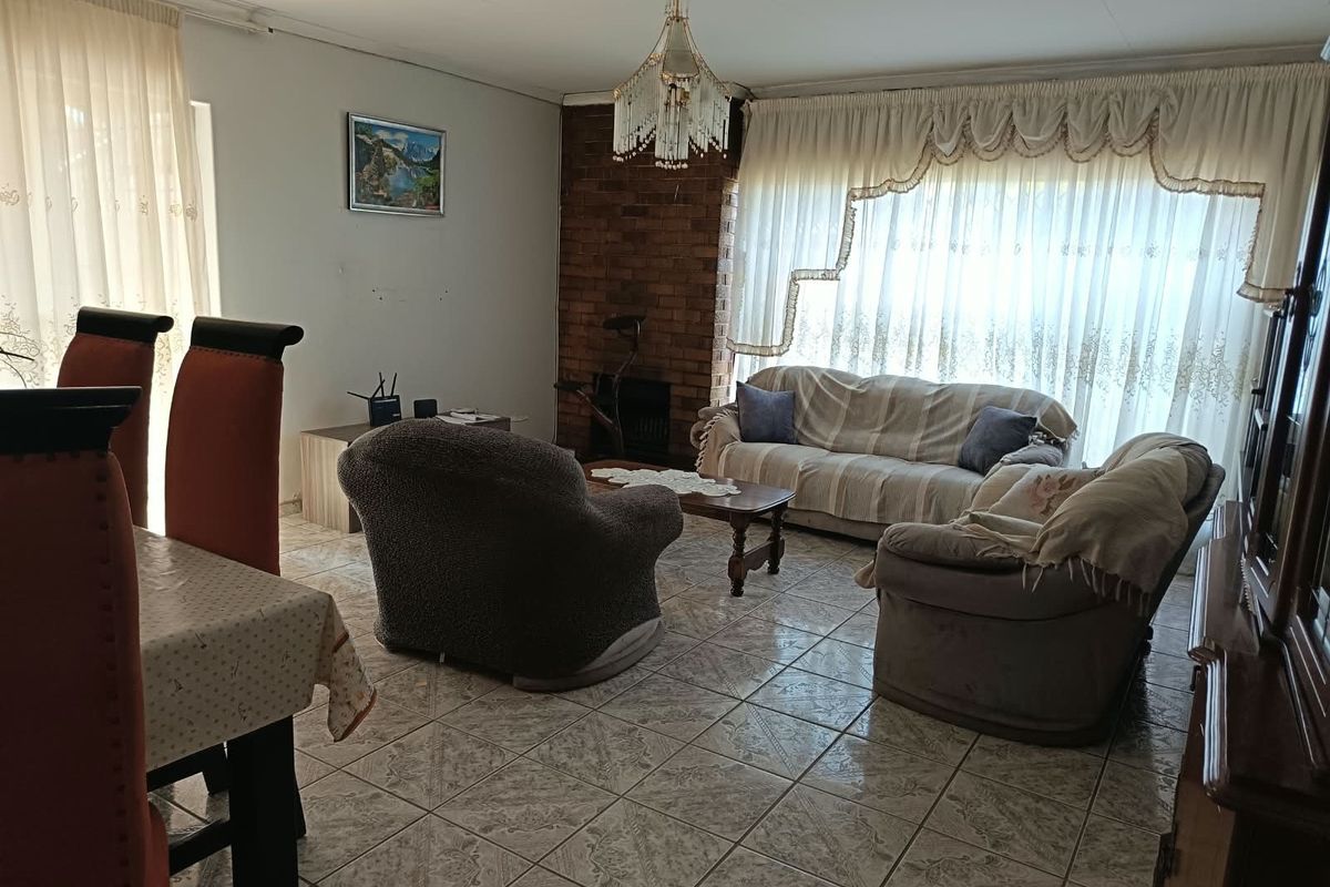 A spacious living area featuring tiled flooring and a classic brick fireplace, offering a comfortable and functional layout for family relaxation.