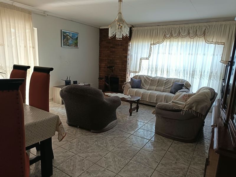 A spacious living area featuring tiled flooring and a classic brick fireplace, offering a comfortable and functional layout for family relaxation.