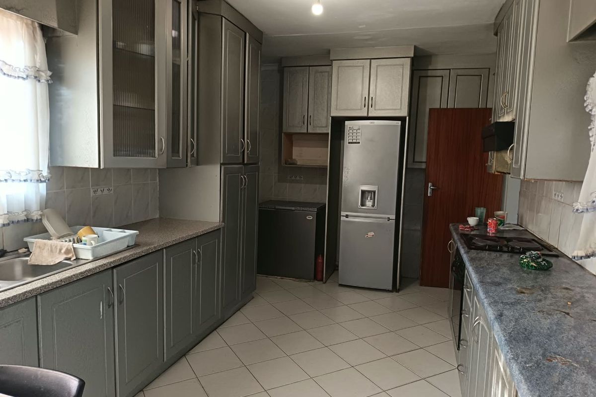 A functional kitchen featuring extensive built-in cabinetry, tiled flooring, and a tiled backsplash, offering a practical layout with ample storage space.
