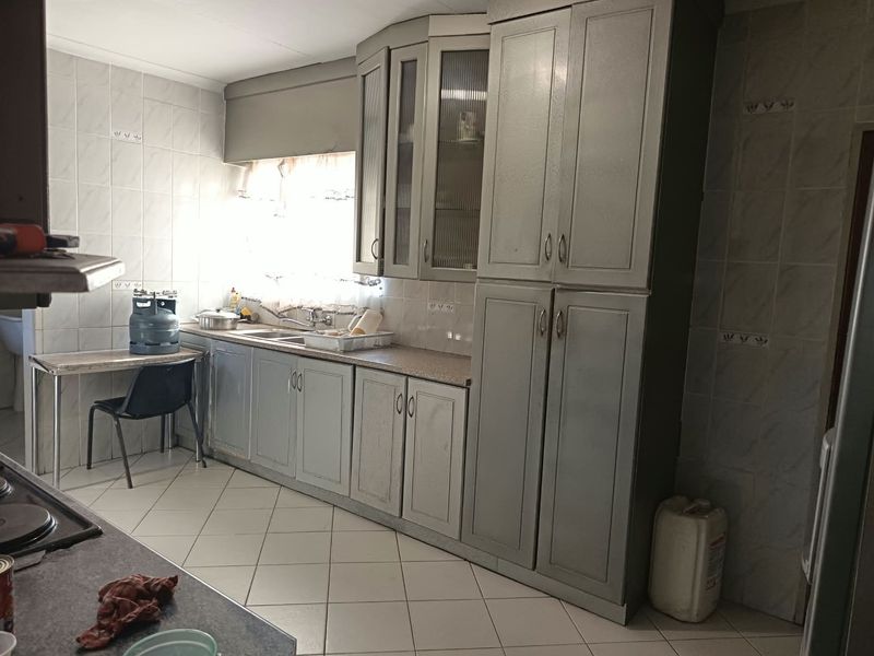 A functional kitchen featuring built-in cabinetry, tiled walls, and tiled flooring, offering a dated aesthetic that could benefit from modern updates.