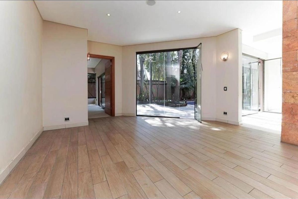 A bright, modern living area featuring timber-look floor tiles, a stone feature wall, and large glass doors providing seamless access to the outdoor space.