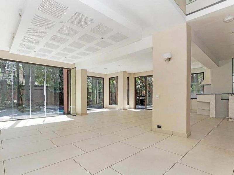 Spacious open-plan living area featuring large format floor tiles, a unique recessed ceiling panel, and bi-fold glass doors opening to the outdoor pool area.