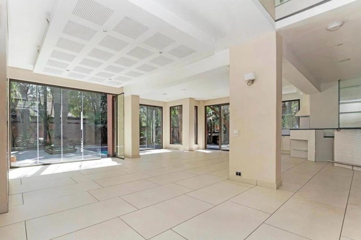 Spacious open-plan living area featuring large format floor tiles, a unique recessed ceiling panel, and bi-fold glass doors opening to the outdoor pool area.