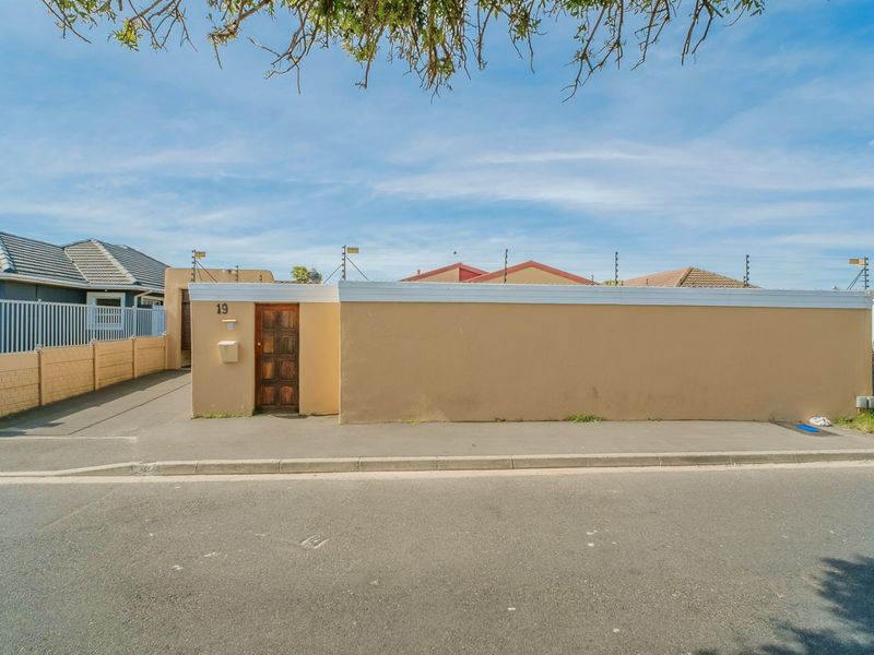 Front view of the property featuring a solid boundary wall, electric fencing, and a private driveway entrance.