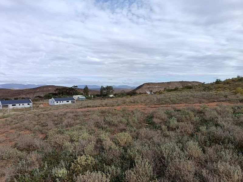 A wide-angle view of the vacant residential land featuring natural scrub vegetation and distant mountain scenery.