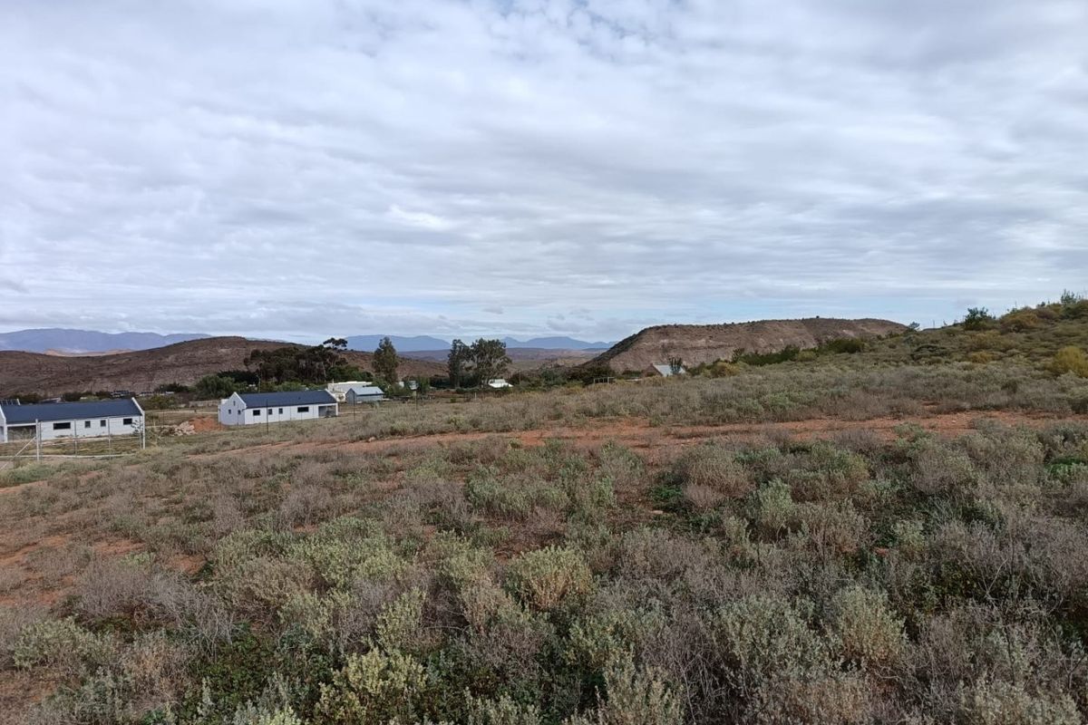 A wide-angle view of the vacant residential land featuring natural scrub vegetation and distant mountain scenery.