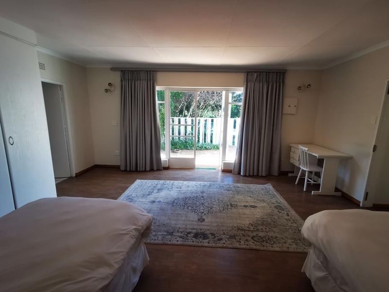 Spacious bedroom featuring laminate flooring, built-in cupboards, and a sliding glass door providing access to an outdoor area.