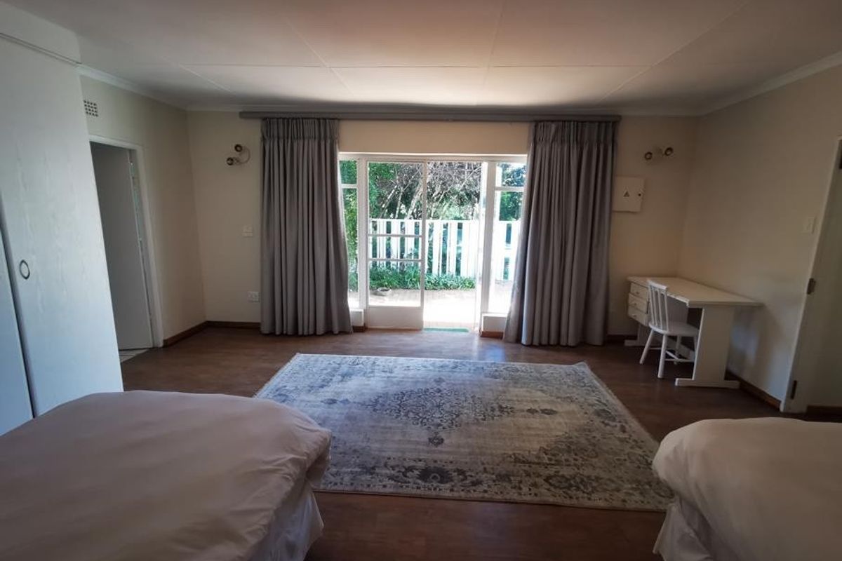Spacious bedroom featuring laminate flooring, built-in cupboards, and a sliding glass door providing access to an outdoor area.