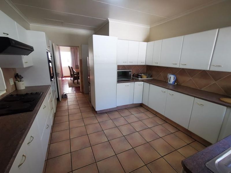 Functional kitchen featuring white cabinetry, laminate countertops, tiled backsplash, and ceramic flooring, offering a practical layout with integrated cooking appliances.