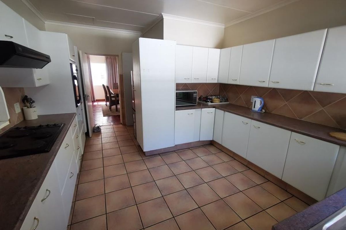 Functional kitchen featuring white cabinetry, laminate countertops, tiled backsplash, and ceramic flooring, offering a practical layout with integrated cooking appliances.
