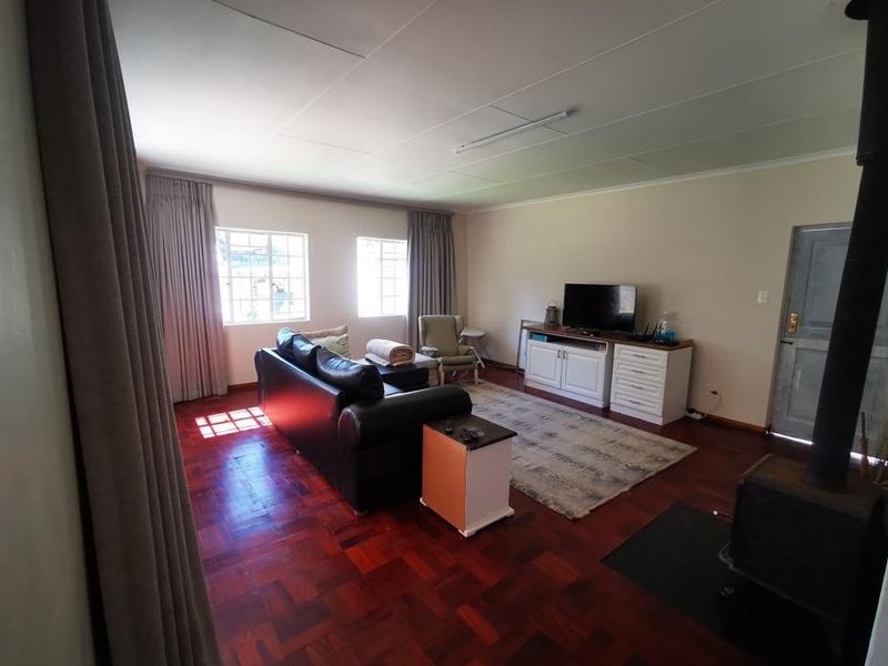 Spacious living room featuring warm parquet flooring and a built-in wood-burning fireplace, offering a comfortable and inviting atmosphere.