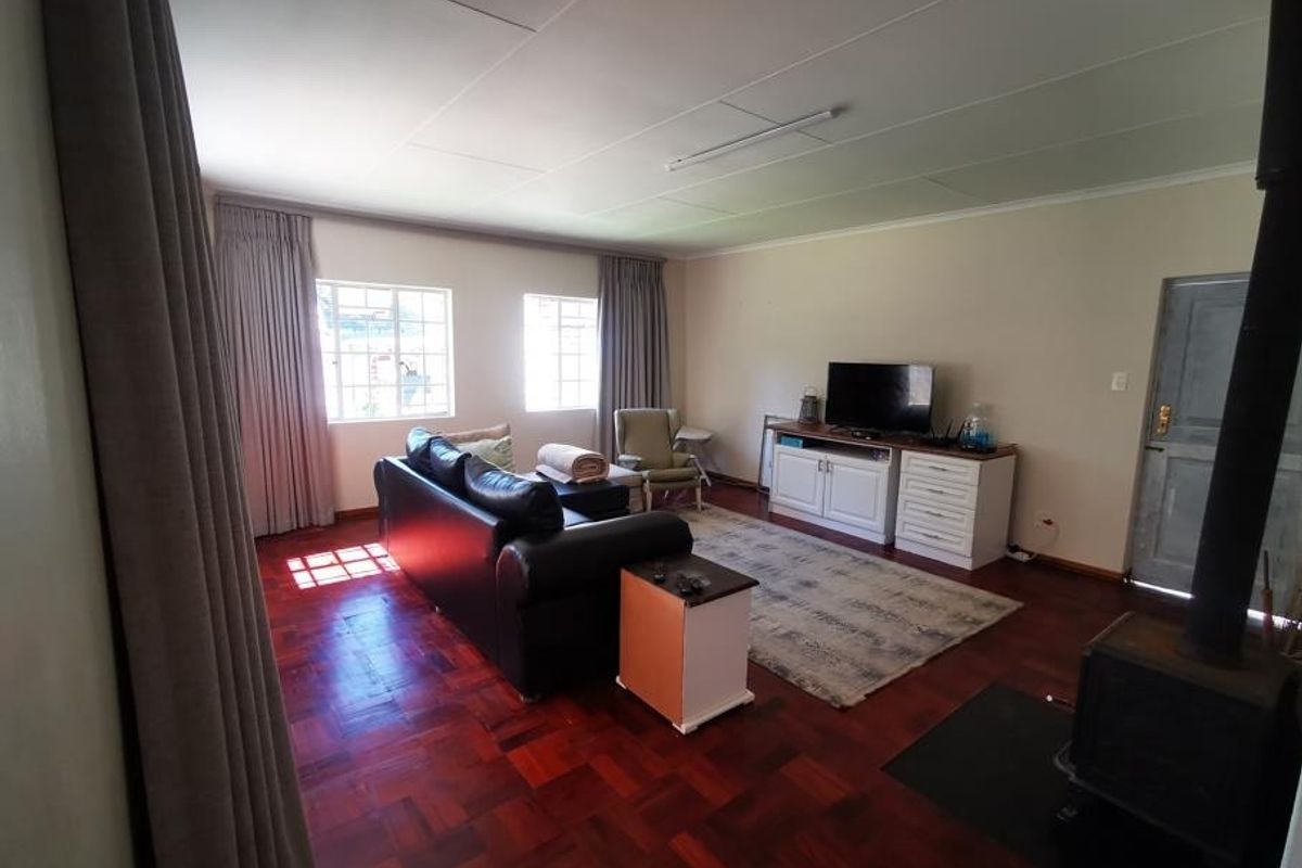 Spacious living room featuring warm parquet flooring and a built-in wood-burning fireplace, offering a comfortable and inviting atmosphere.