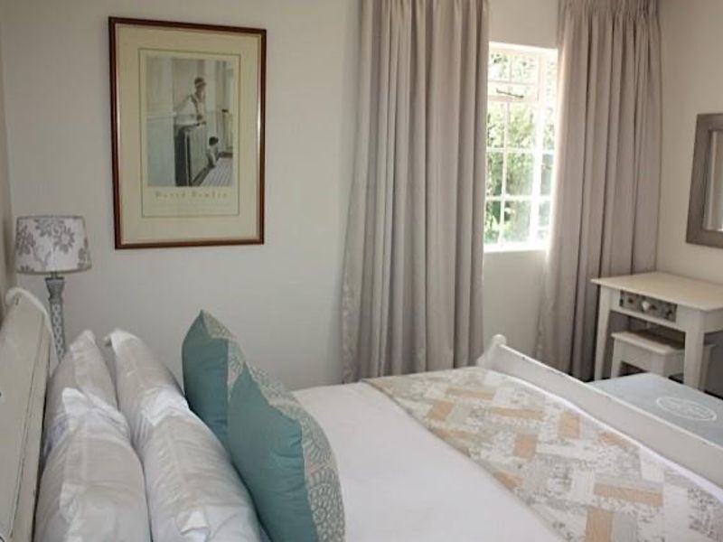 A cozy bedroom featuring neutral wall tones, a window with floor-length curtains, and a functional layout suitable for a comfortable sleeping space.