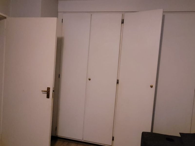 A bedroom interior featuring built-in wardrobes and a standard internal door, presenting a neutral and functional space.