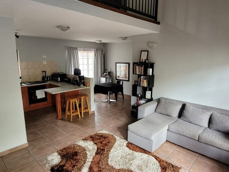 Open-plan living and kitchen area featuring tiled flooring, a mezzanine level, and a functional kitchen layout with built-in cabinetry.
