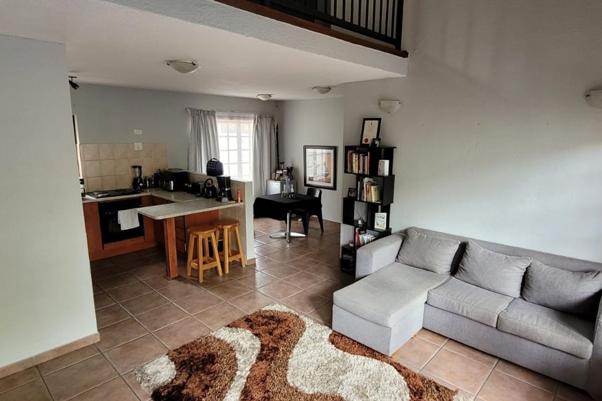 Open-plan living and kitchen area featuring tiled flooring, a mezzanine level, and a functional kitchen layout with built-in cabinetry.