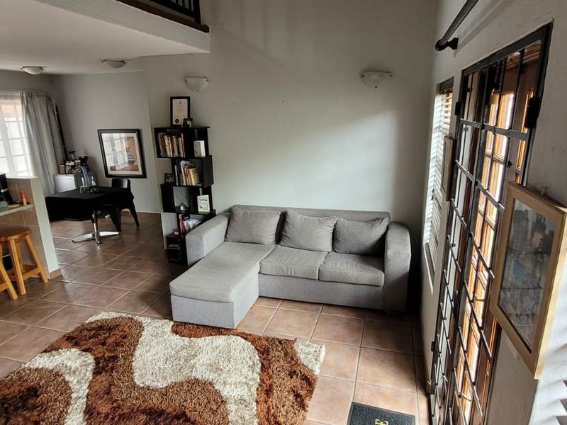 Open-plan living area featuring tiled flooring, a functional kitchen with built-in cabinetry, and access to outdoor space through classic french doors.