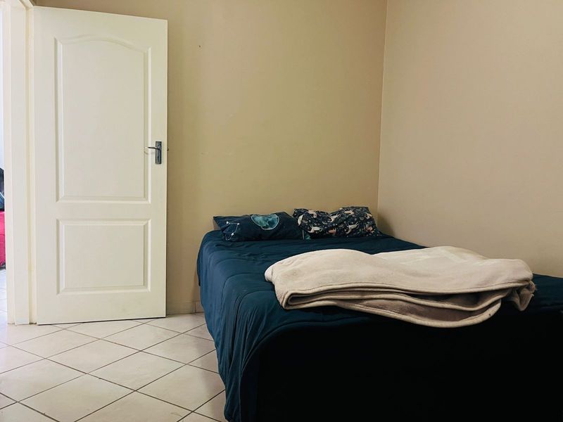 A simple bedroom featuring neutral wall tones and tiled flooring, providing a functional and blank canvas for personalization.