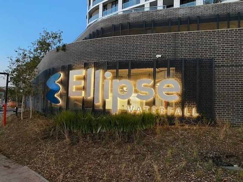 Exterior view of the Ellipse Waterfall apartment complex featuring modern brick architecture and illuminated building signage.
