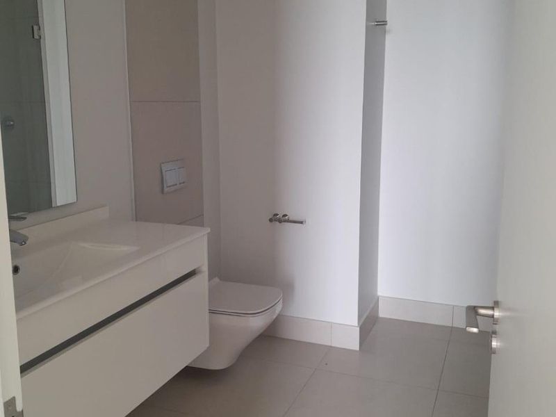 Modern bathroom featuring a wall-mounted vanity with integrated basin, wall-hung toilet with concealed cistern, and neutral tiled flooring.