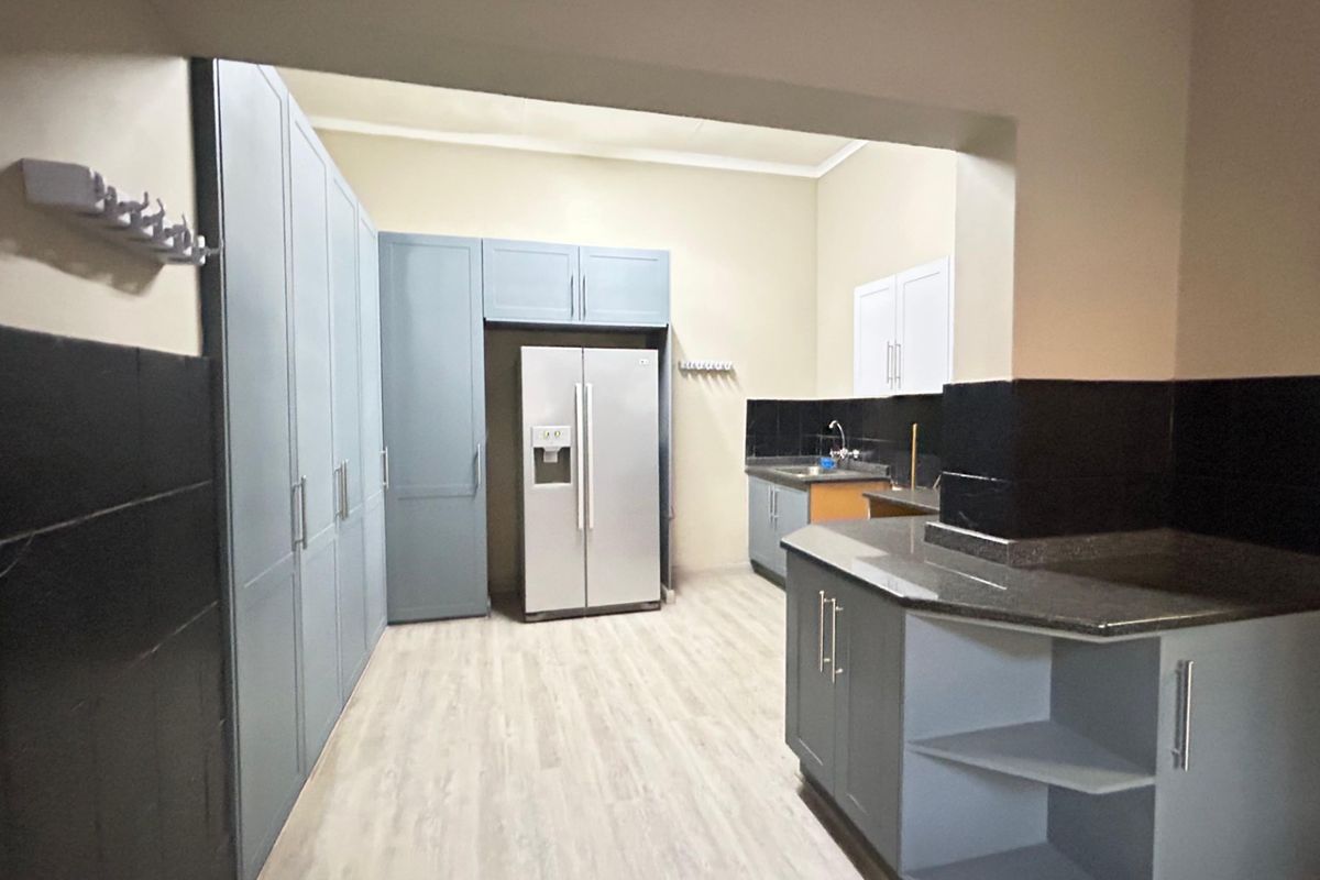 A functional kitchen featuring extensive built-in cabinetry, granite countertops, and a double sink with a tiled splashback.