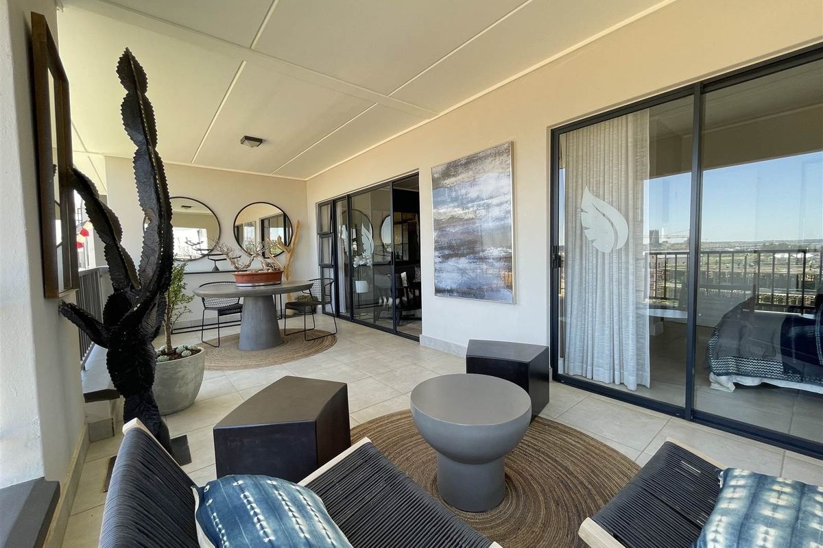 A spacious covered balcony featuring tiled flooring and large sliding glass doors that provide seamless access to the interior living spaces.