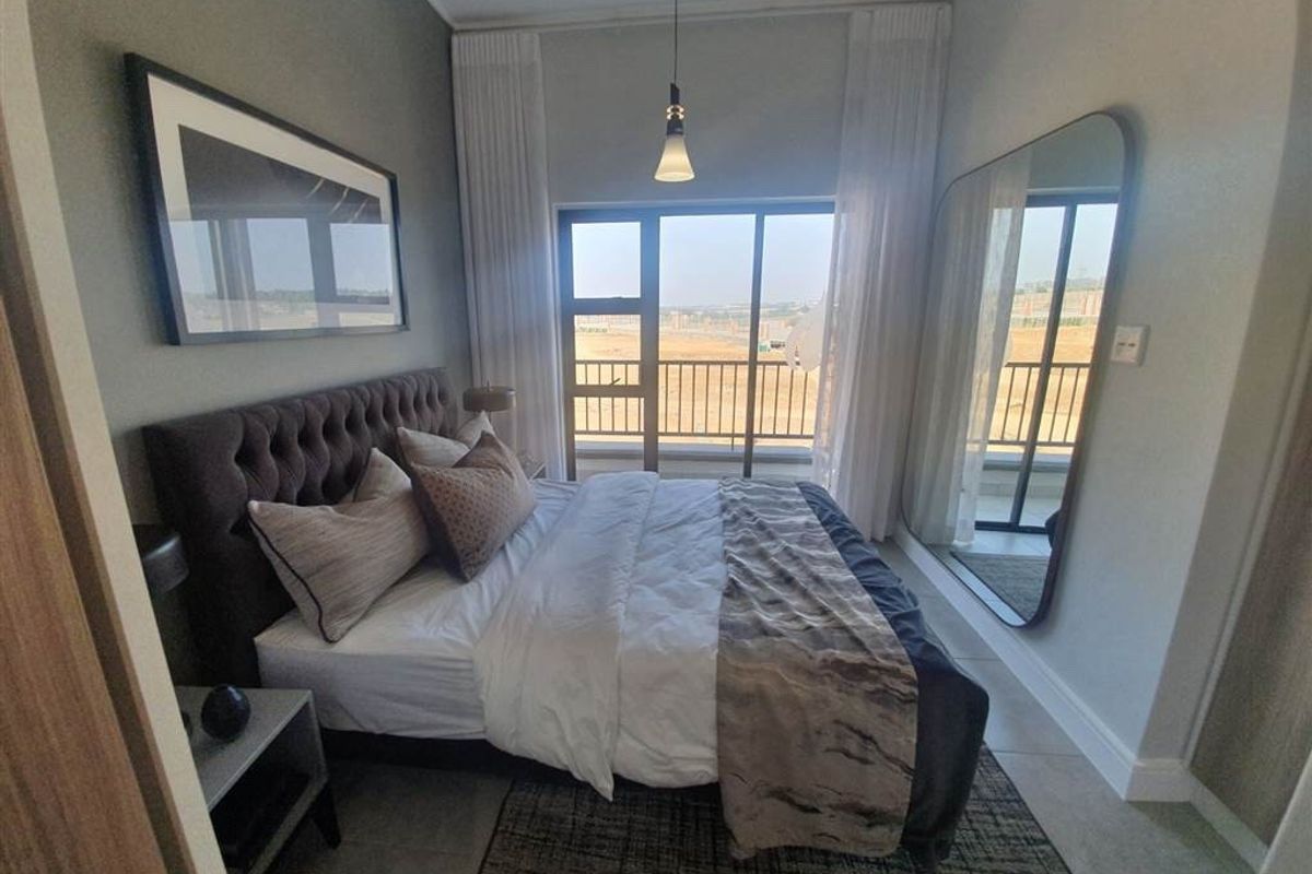 A modern bedroom featuring tiled flooring, a pendant light, and a large sliding glass door providing access to a balcony.