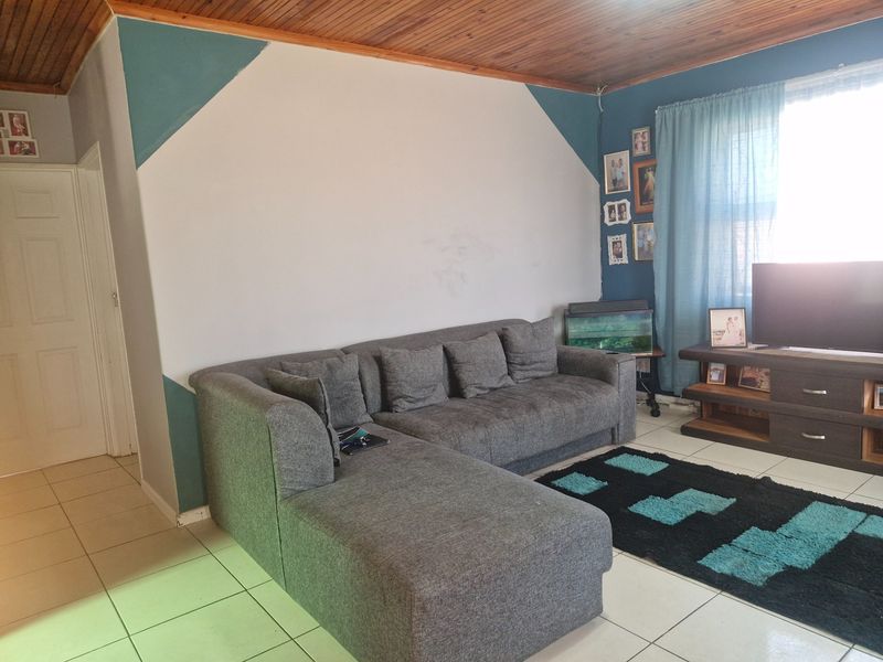 A living room featuring tiled flooring and a timber-paneled ceiling, offering a functional space with potential for cosmetic updates.