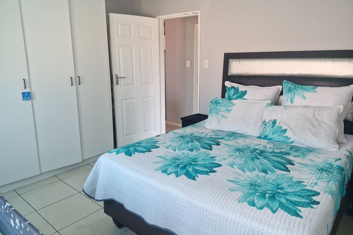 A functional bedroom featuring tiled flooring and built-in cupboards, providing ample storage space.