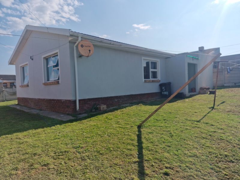 A view of the rear exterior of the house, featuring a brick plinth foundation, casement windows, and a satellite dish mounted on the wall.