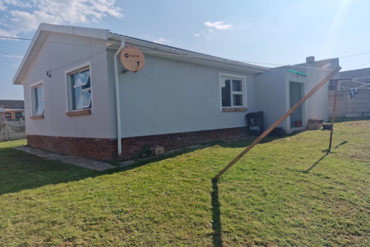 A view of the rear exterior of the house, featuring a brick plinth foundation, casement windows, and a satellite dish mounted on the wall.