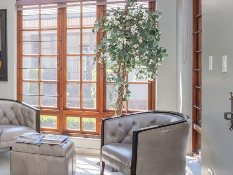 A bright living area featuring large timber-framed windows that provide natural light and a view of the exterior.