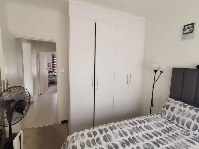 A bedroom featuring a white built-in wardrobe with clean lines and neutral finishes, providing ample storage space.